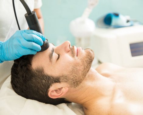 Profile view of a good looking young man getting a RF facial treatment in a health spa